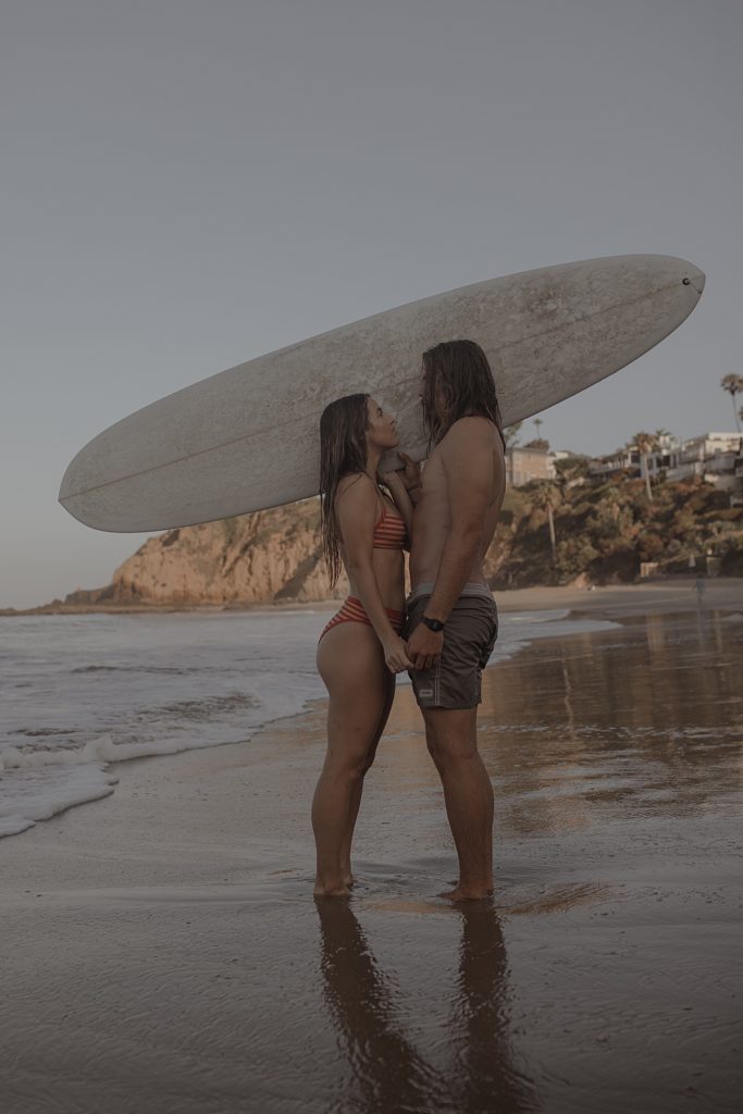 surfer couple holding hands in ocean