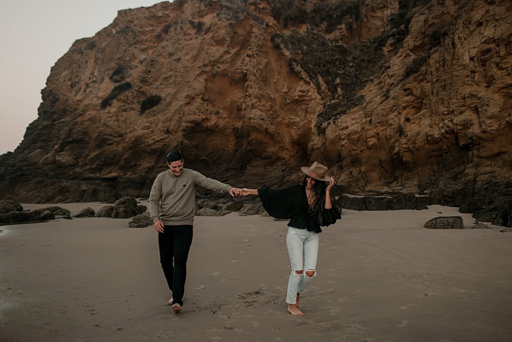 couple holding hands running on beach