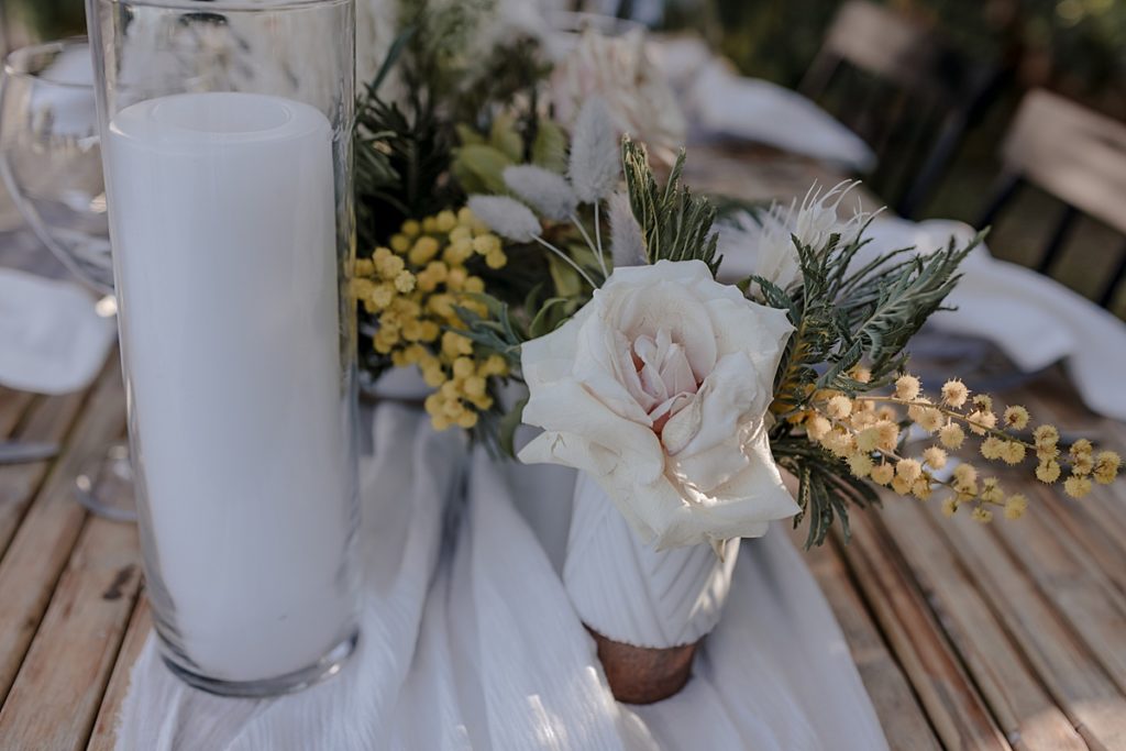 wedding table centerpieces with neutral flowers and white candles and linens