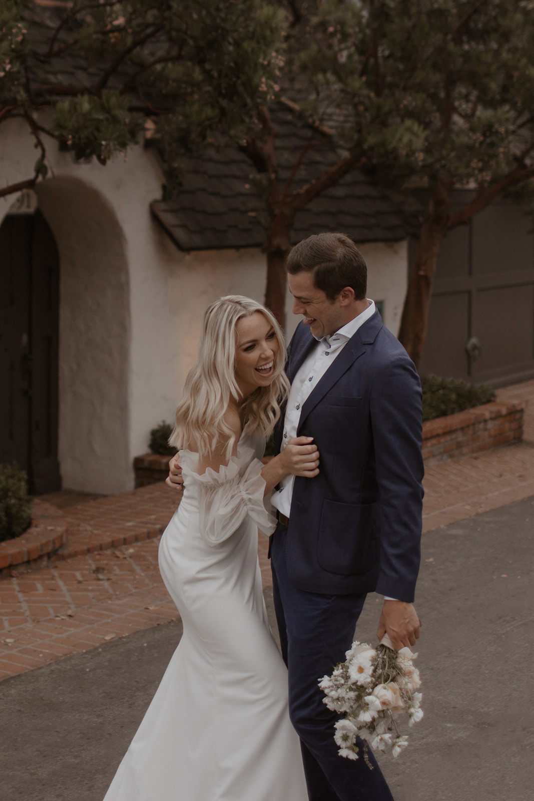 California Coast Blue Hour Elopement at Laguna Beach with bride and groom hugging while bride is holding boho wedding flowers