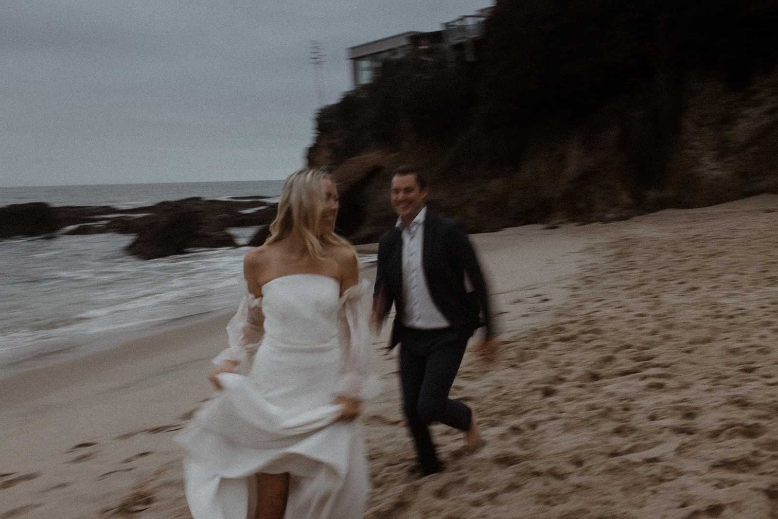bride and groom running on beach at beach elopement in laguna beach