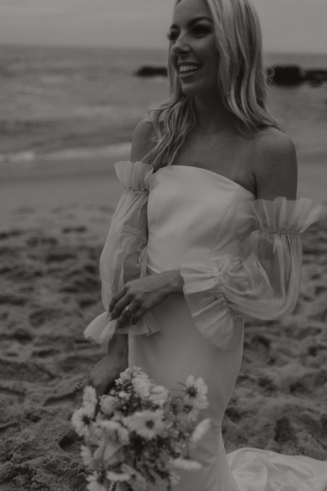 bride holding boho themed wedding flowers on beach