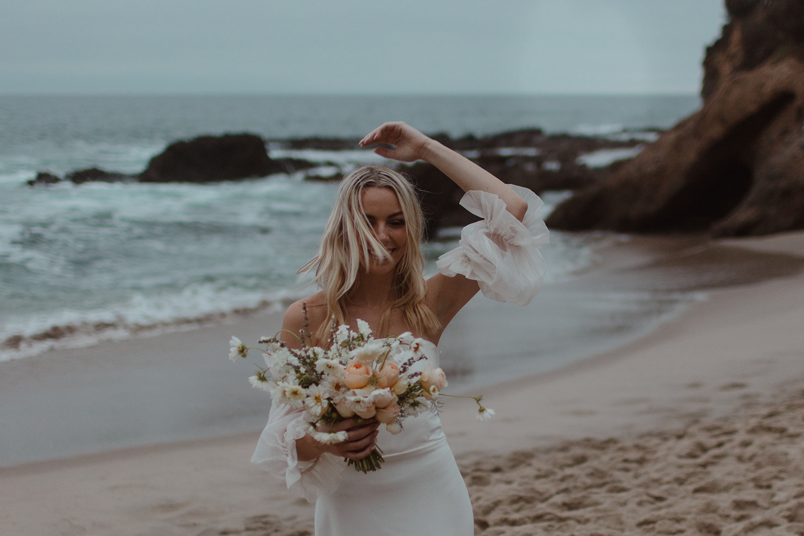 bride holding boho themed wedding flowers on beach