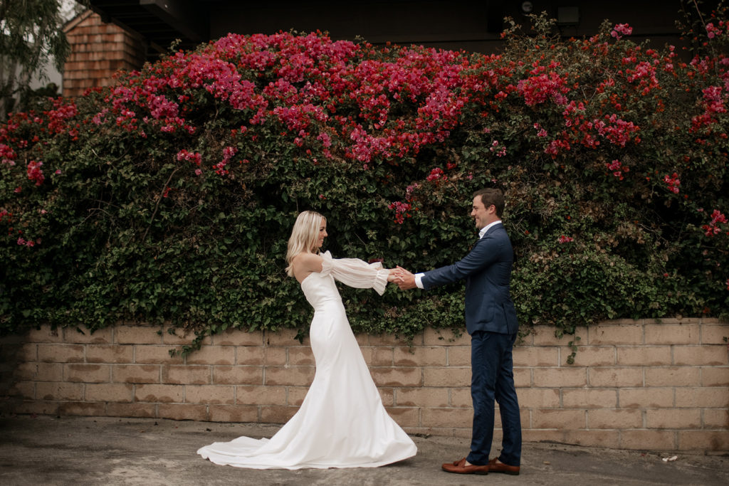 California Coast Blue Hour Elopement at Laguna Beach with bride and groom holding each other and beautiful flower backdrops