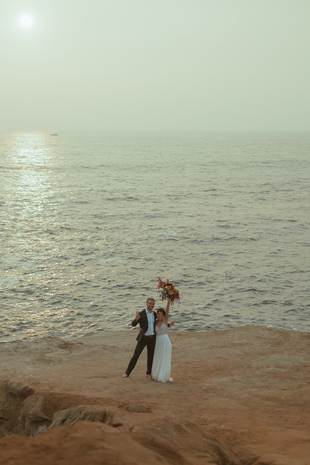 bride and groom dancing on cliff side in san diego with beautiful beach backdrop