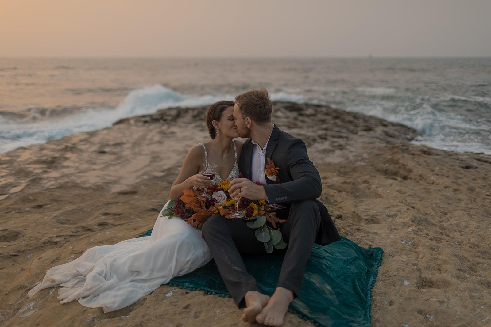 bride and groom sitting on cliffside during beach elopement in san diego 