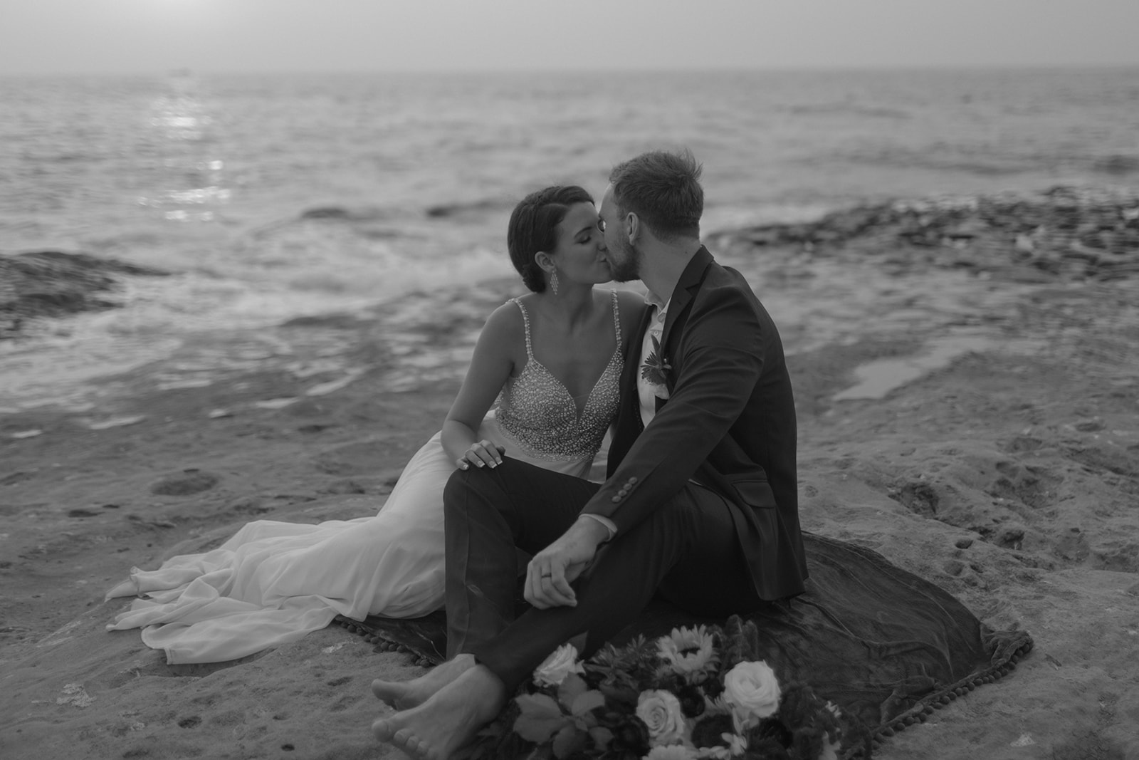 bride and groom sitting on cliffside during beach elopement in san diego 