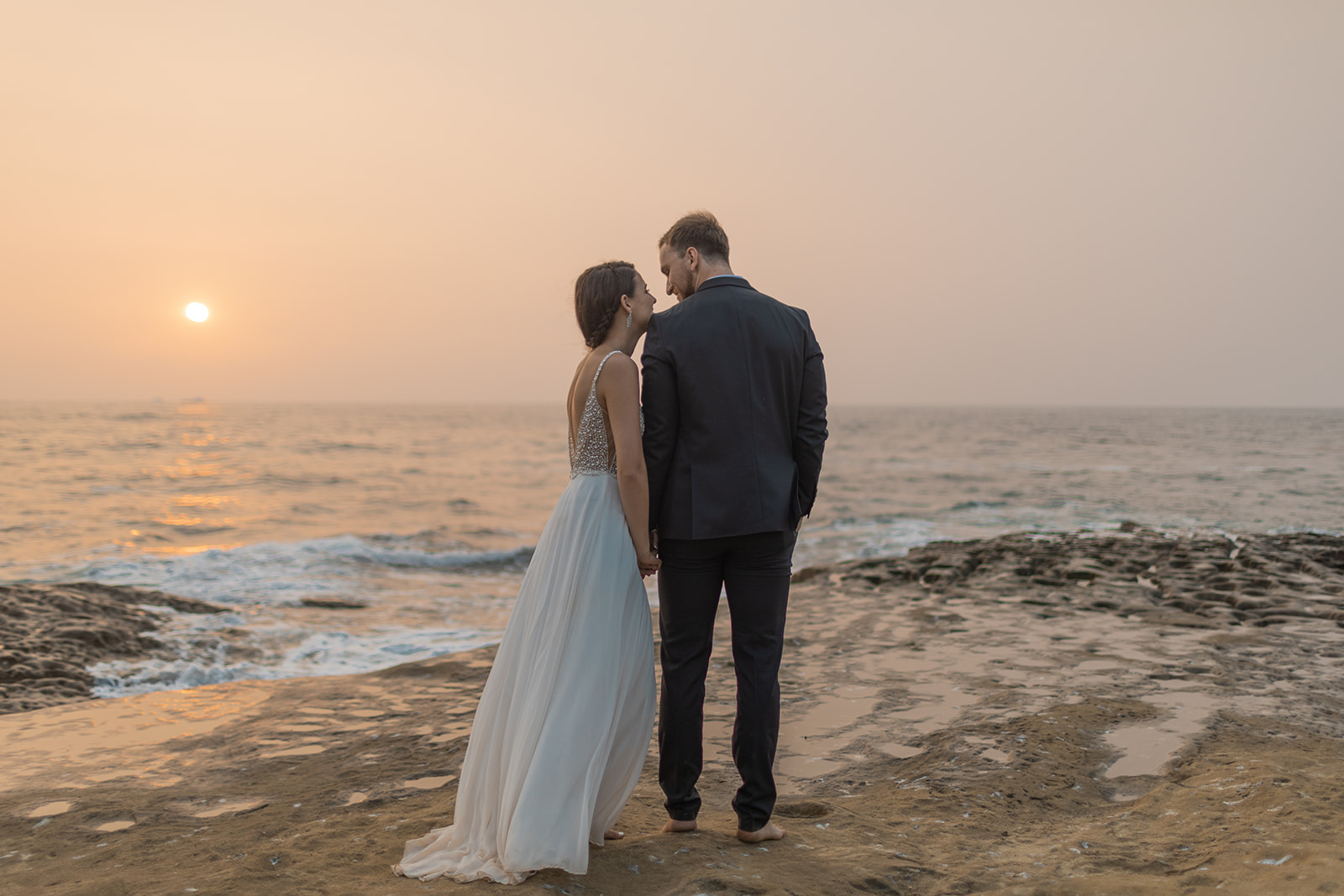 bride and groom standing on cliffside during beach elopement in san diego 