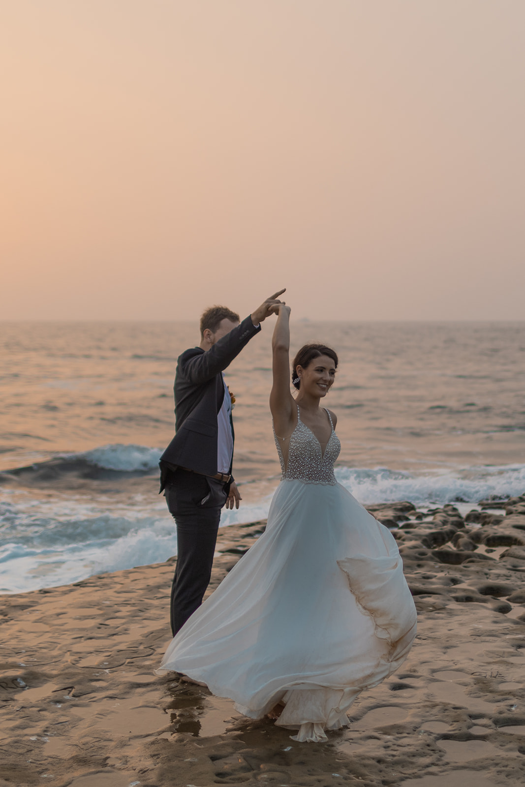 bride and groom dancing on cliffside during beach elopement in san diego 