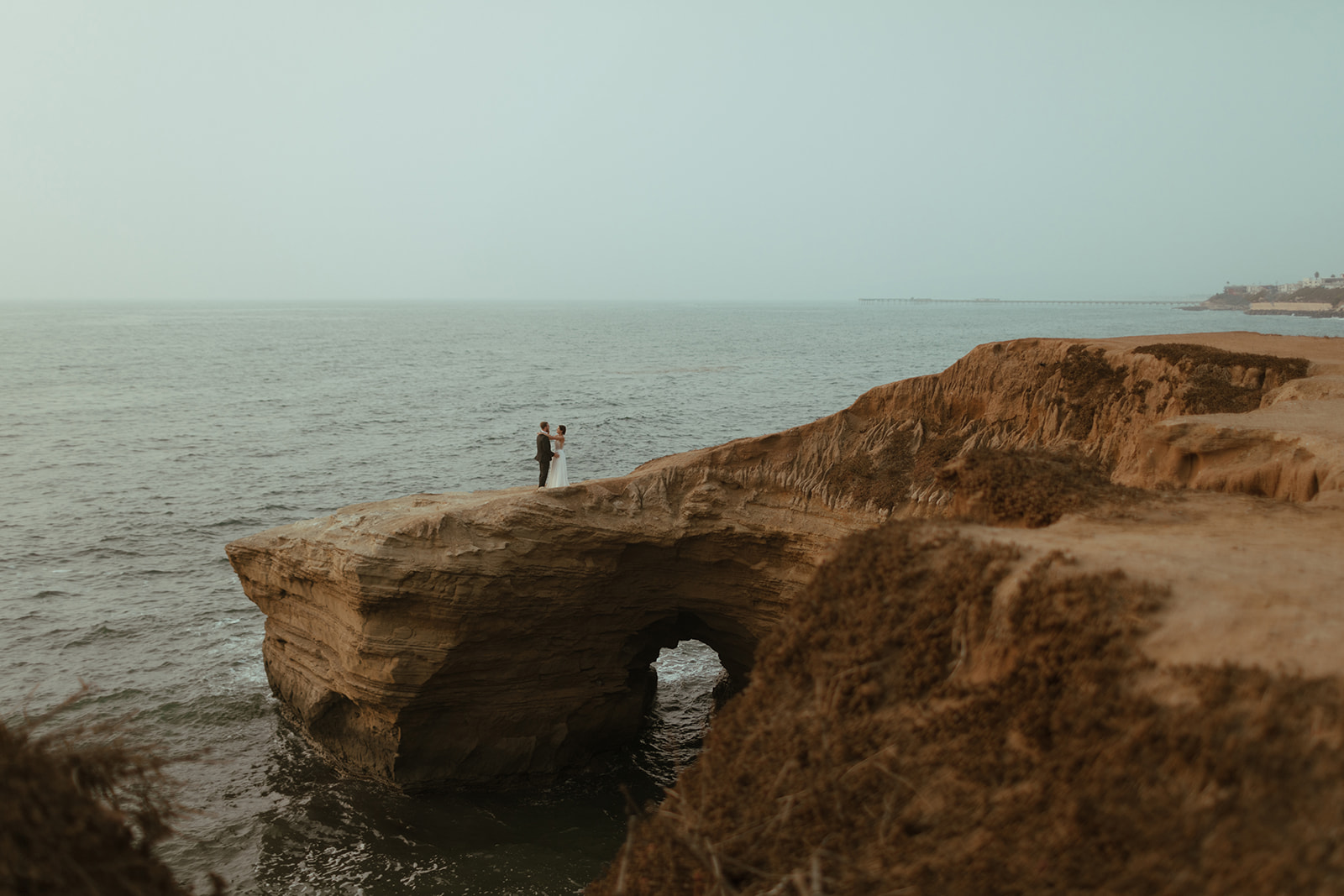 San Diego Elopement at Sunset Cliffs with bride and groom holding each other on cliffside