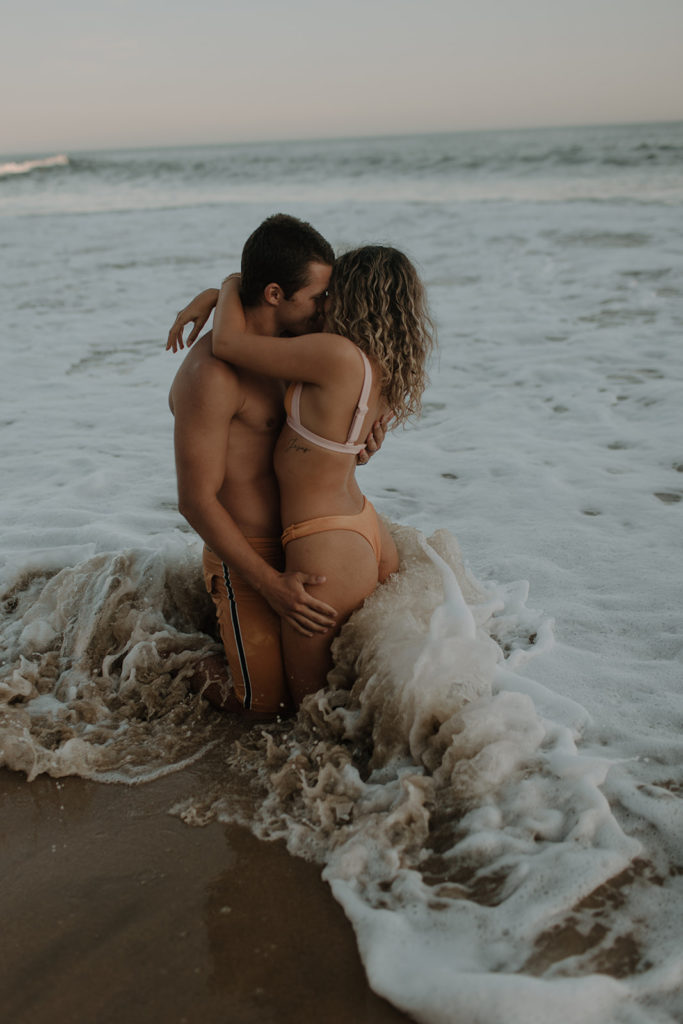 couple sitting in ocean kissing and hugging