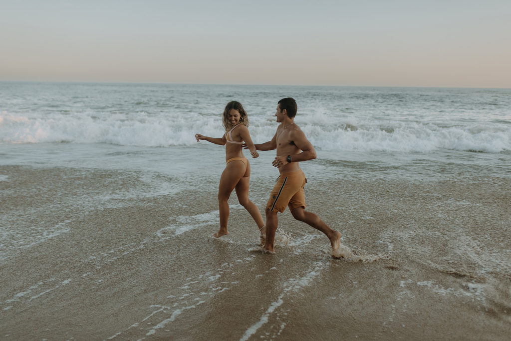 couple running on beach holding hands