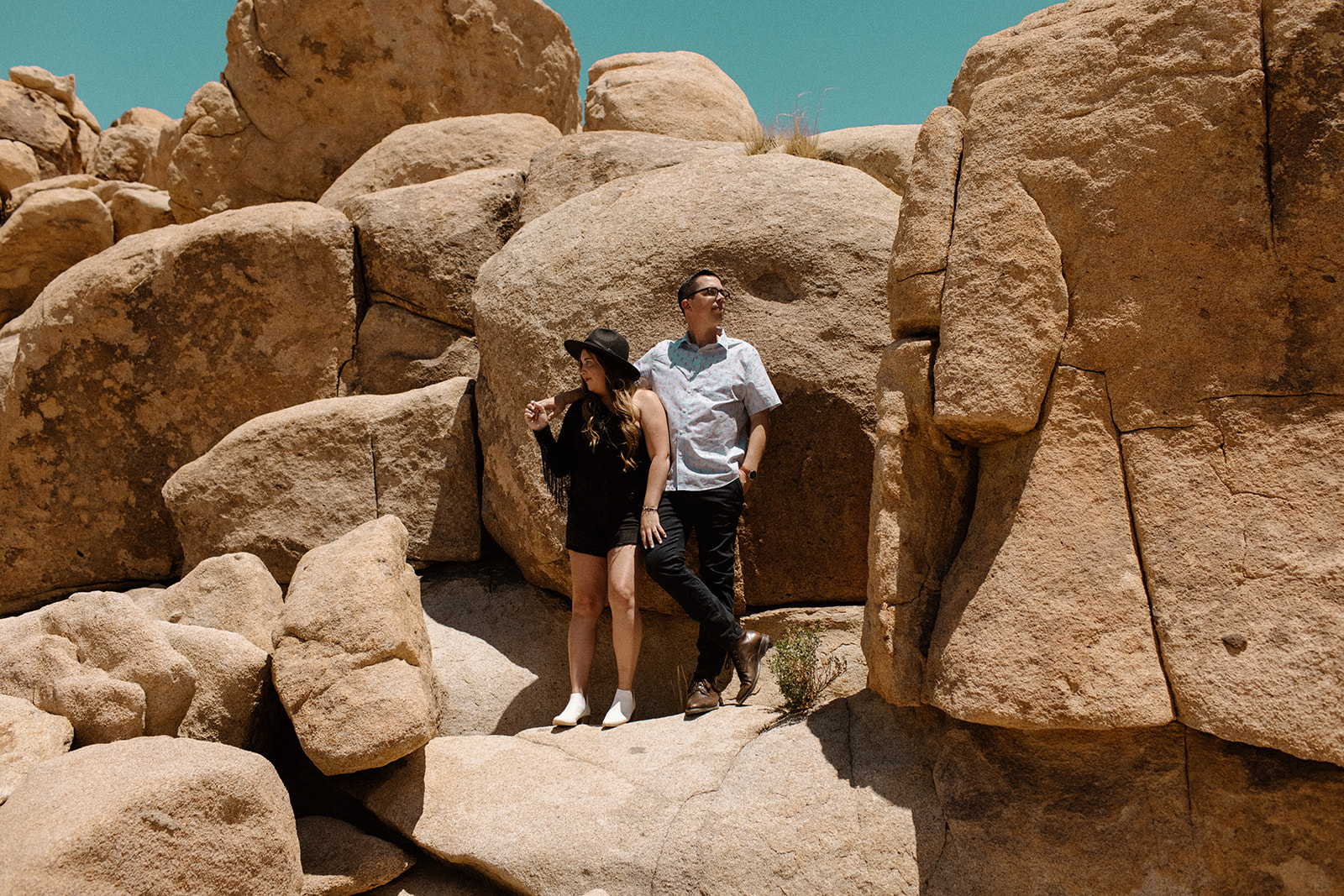 couple standing on rock at joshua tree for engagement photoshoot