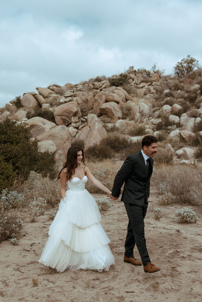 couple holding hands at wedding in the desert