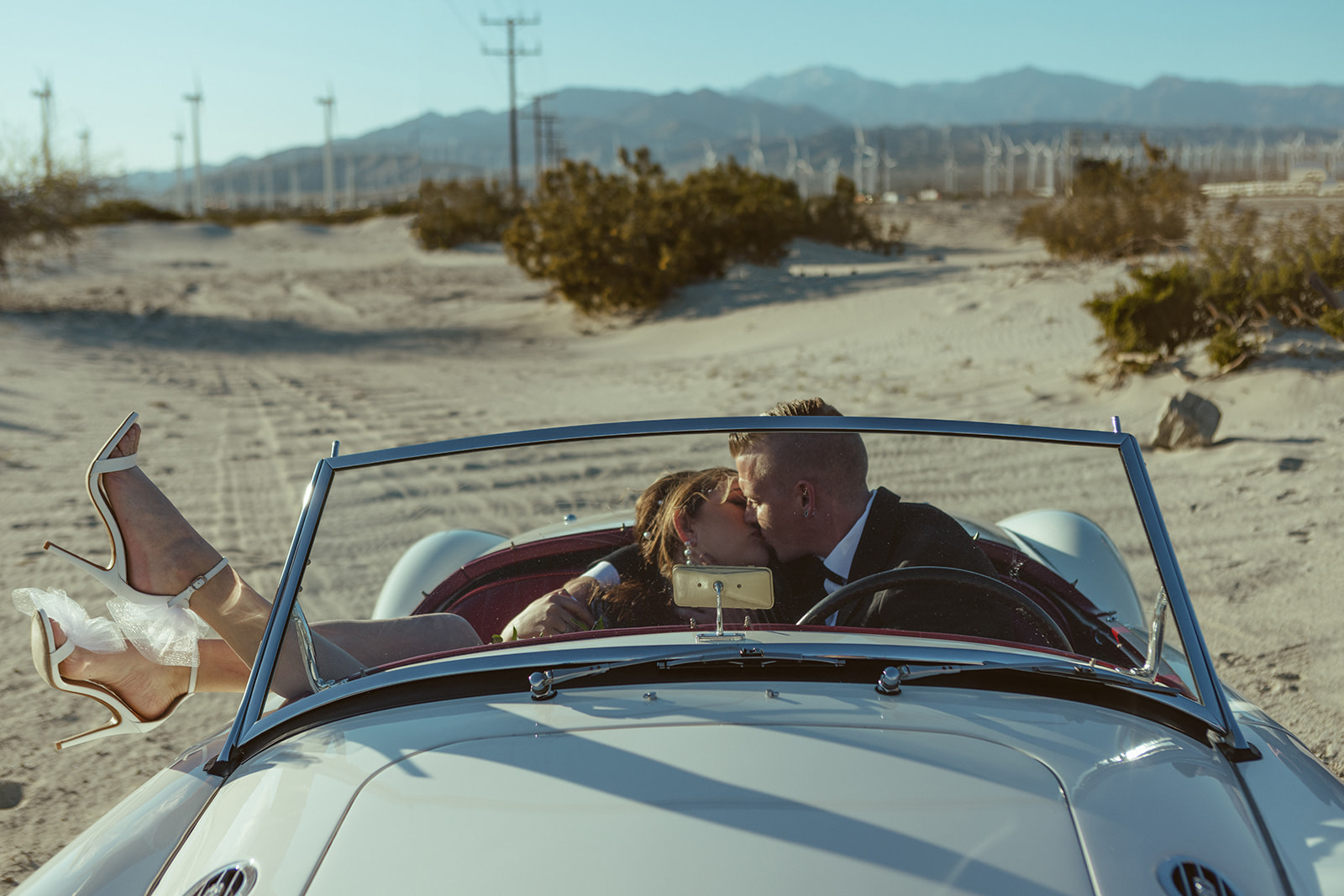 retro elopement in palm springs with couple sitting in retro car kissing