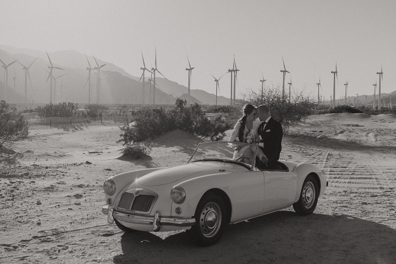 Retro Palm Springs Elopement || Ariel + Travisretro themed elopement at windmills of palm springs with couple sitting in retro car