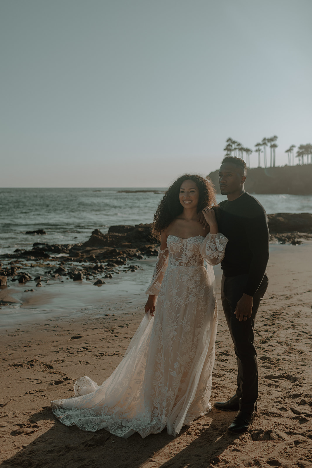 elopement on beach with couple holding each other and bride wearing a long sleeve boho wedding dress
